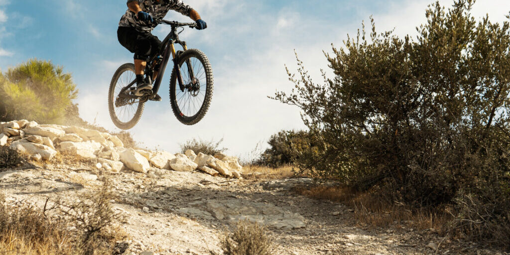 Professional bike rider jumping during downhill ride on his bicycle in mountains
