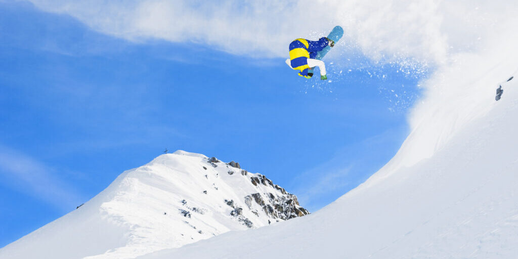 Extreme Snowboarding. Freestyle snowboarder jumping in the air. Blue sky in the background. Powder snow.SEE ALSO: