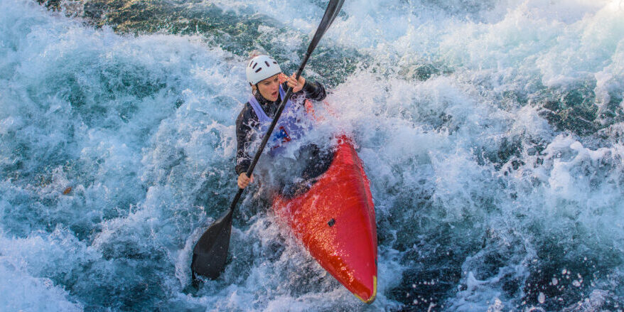 Woman rowing oar while enjoying kayaking in white water.