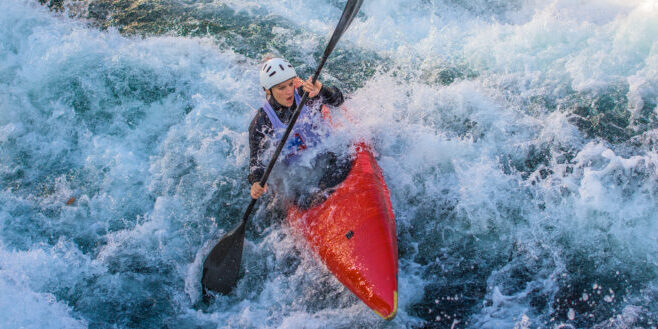Woman rowing oar while enjoying kayaking in white water.